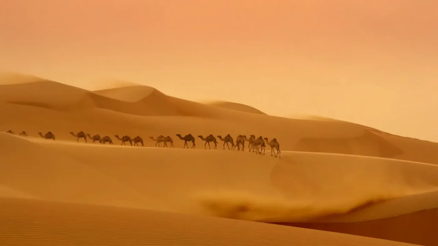 Generiertes Standbild: eine Kamelkarawane zieht über Sanddünen